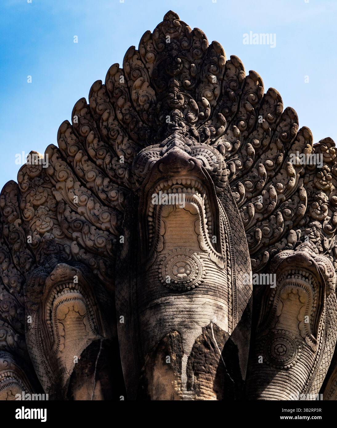 Una vista ravvicinata di una scultura in pietra che presenta un serpente a più teste, conosciuto come Naga, con intricate incisioni e dettagli. La scultura è ambientata in agains Foto Stock