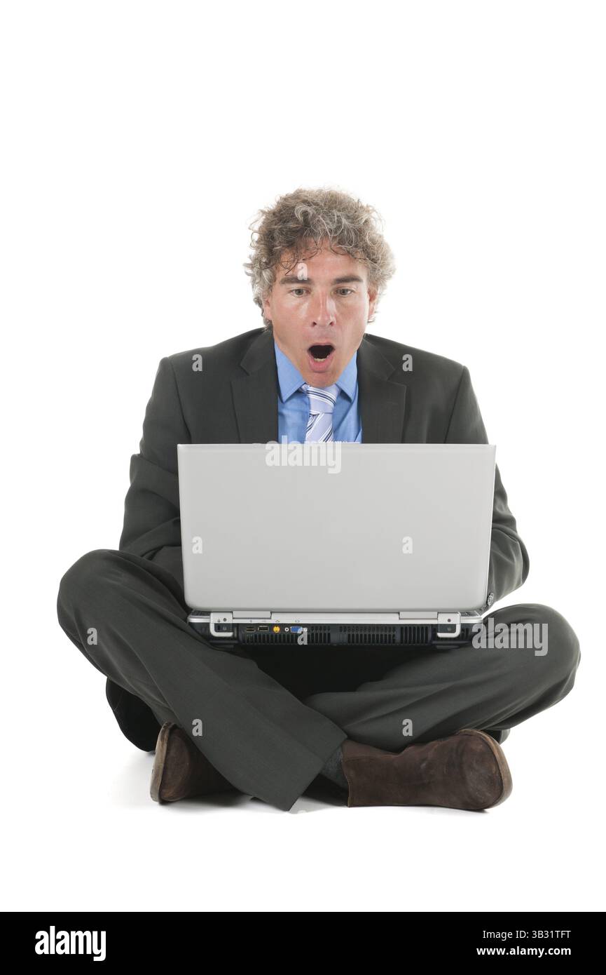 L'uomo la posa sul pavimento mentre si lavora con il computer portatile Foto Stock