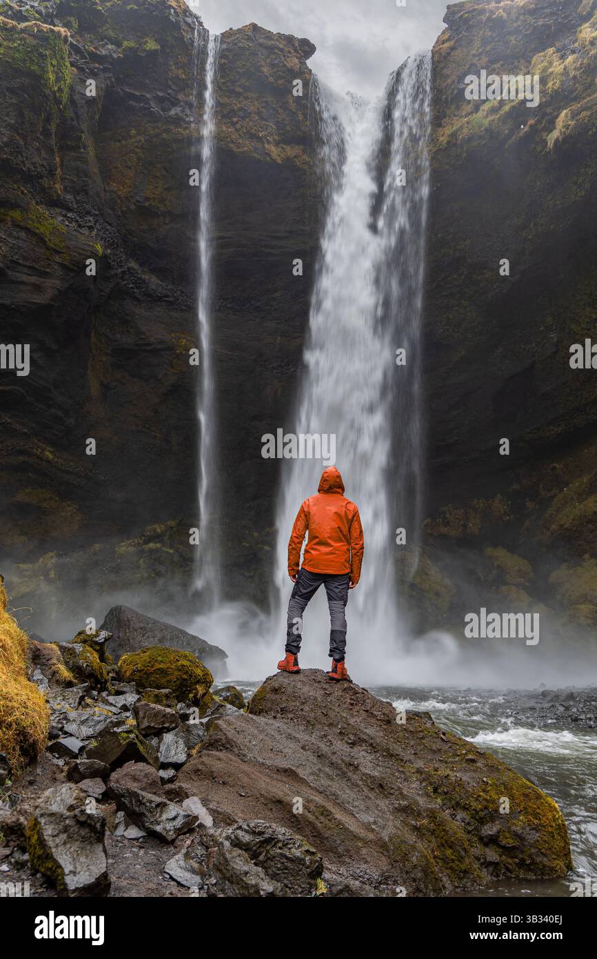 La potente cascata Kvernufoss con un giovane inidentificabile retroscena sulla roccia Foto Stock