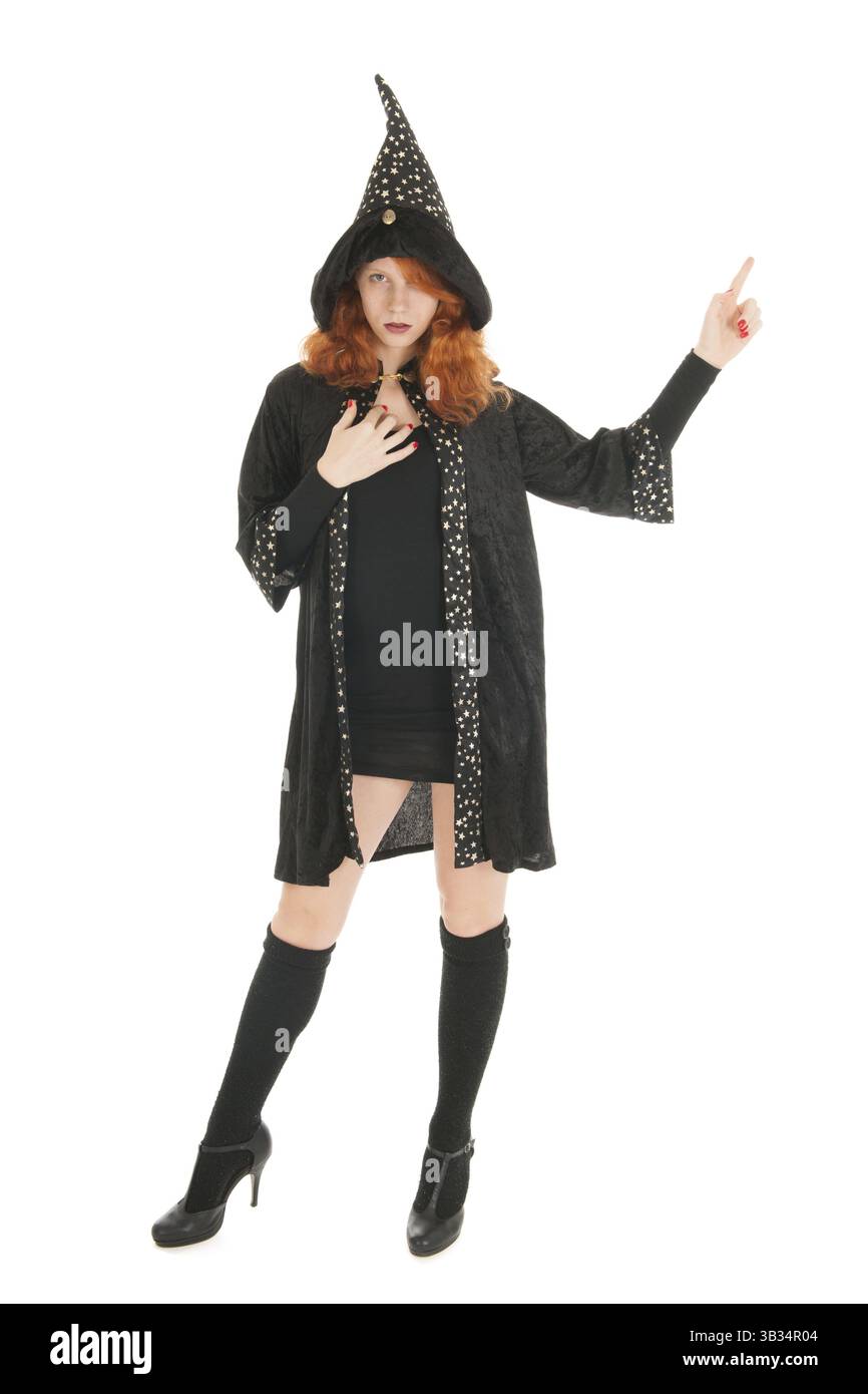 Giovane donna con i capelli rossi che punta con il dito come una strega isolata su sfondo bianco Foto Stock