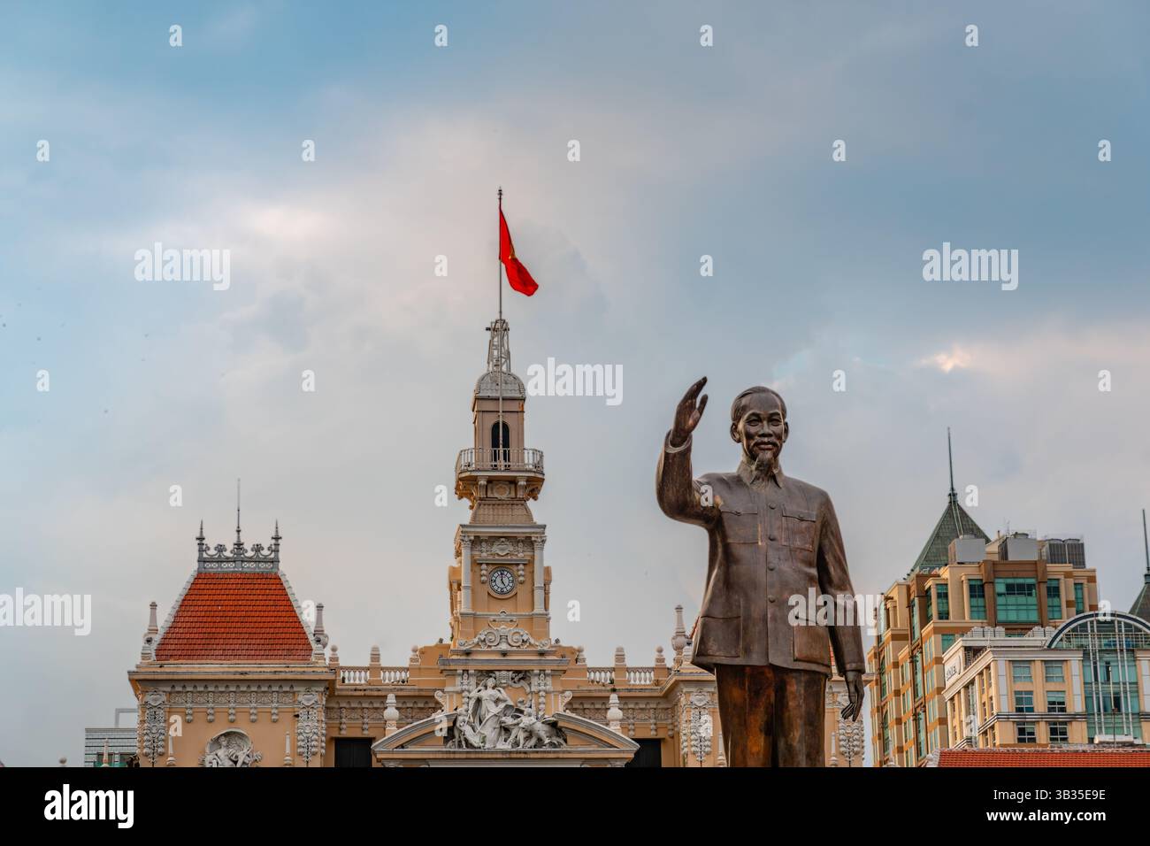 Ho chi Minh City (Saigon), Vietnam - 15 febbraio 2025: Statua di ho chi Minh sulla passeggiata di Nguyen Hue con l'edificio governativo UBND Thành. Foto Stock