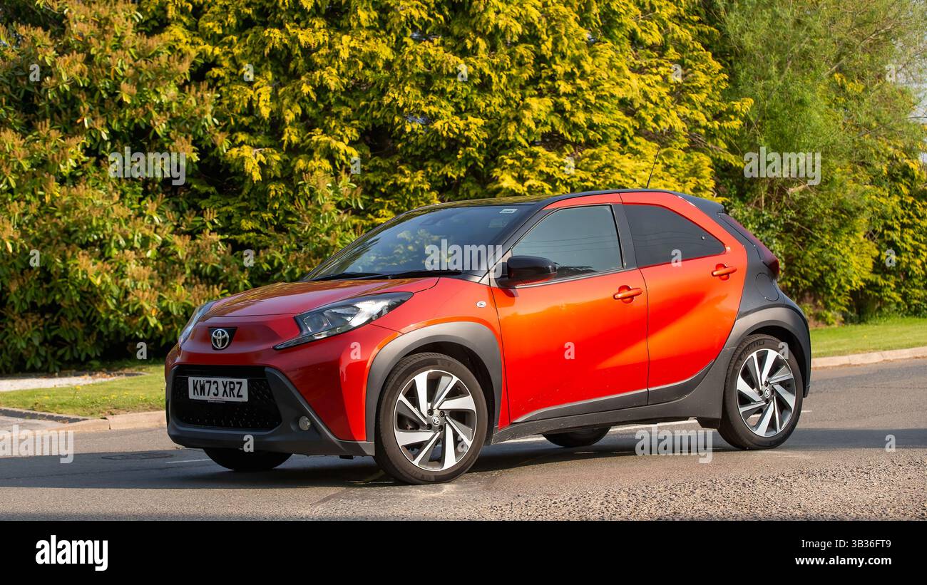 Whittlebury, Northants.,.UK - 27 aprile 2025: 2024 auto Toyota Aygo X Edge rossa che guida su una strada di campagna inglese. Foto Stock