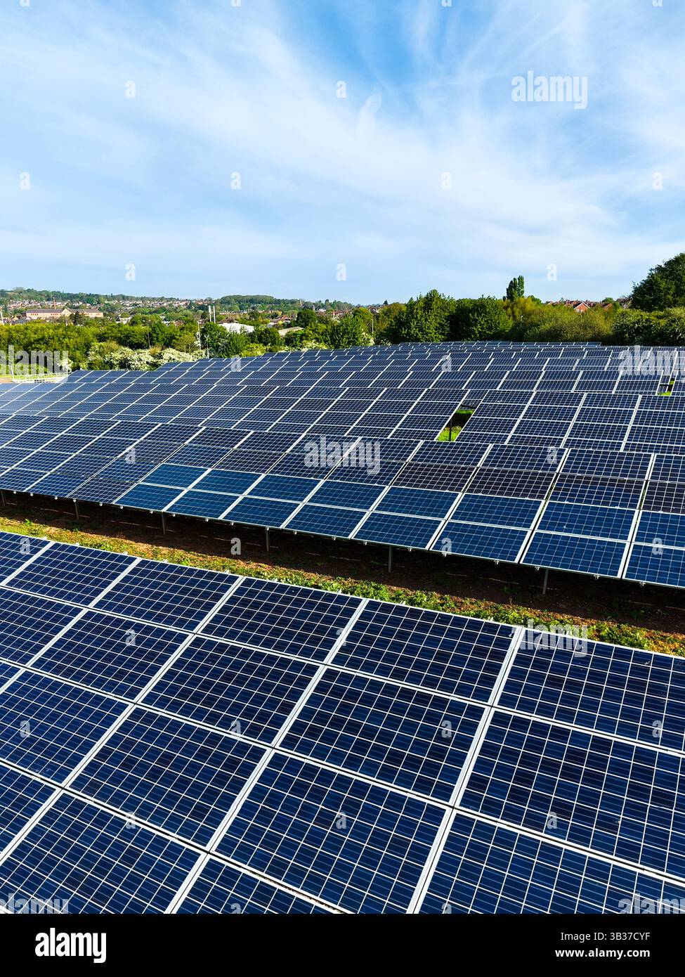 File di pannelli solari fotovoltaici su terreni agricoli che generano energia pulita e sostenibile per uso aziendale e domestico Foto Stock