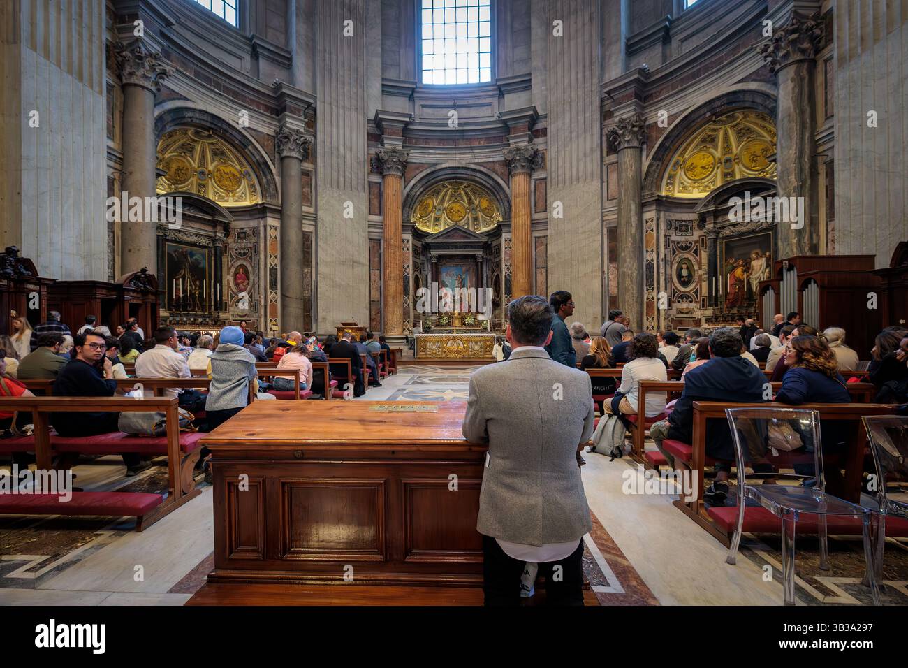 Città del Vaticano, Vaticano - 25 aprile 2025: Alcuni fedeli pregano in una cappella laterale della Basilica di San Pietro il giorno prima del funerale di Papa Francesco. Foto Stock