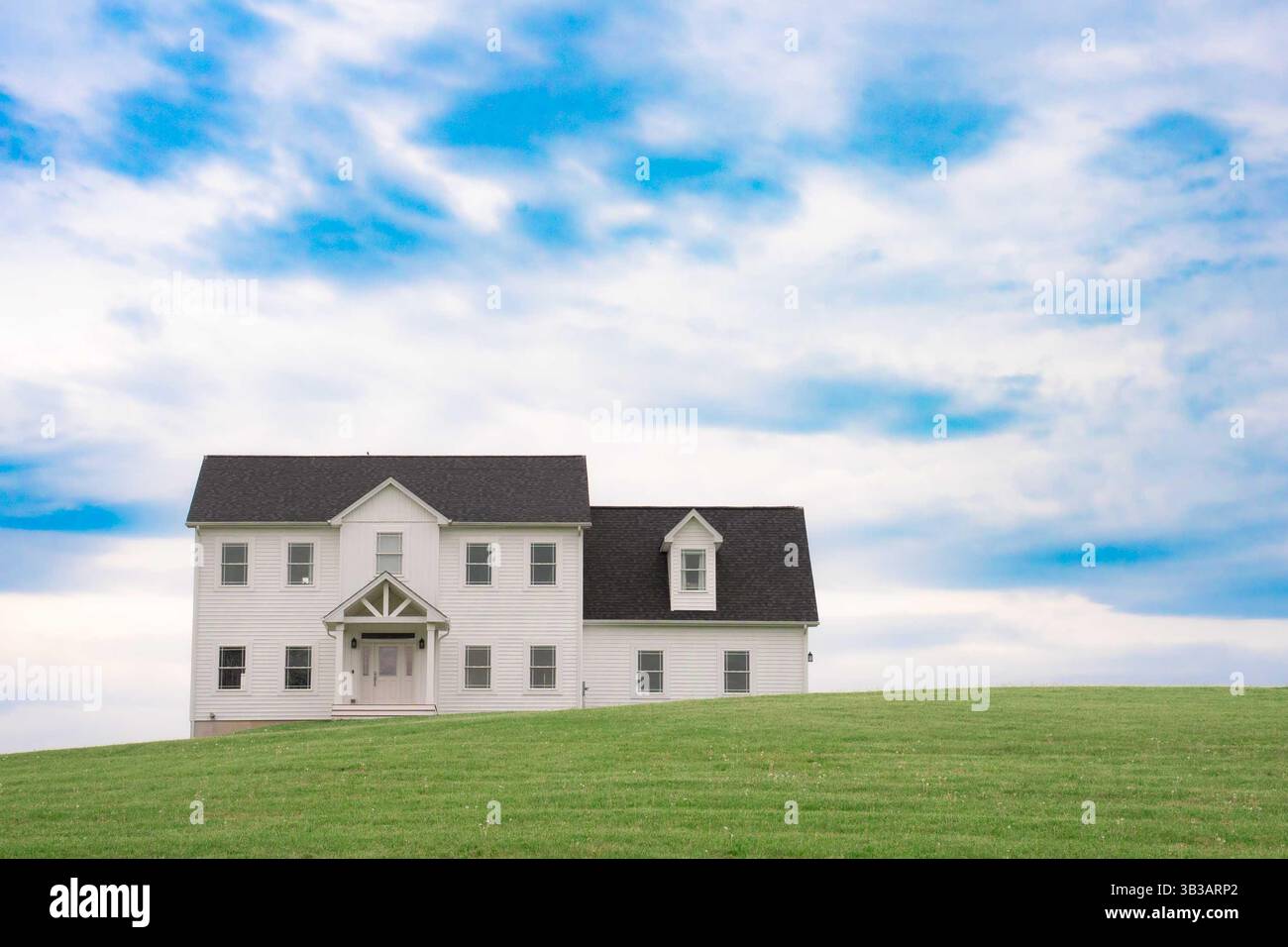 Casa bianca idilliaca con prato verde erboso e cielo blu Foto Stock