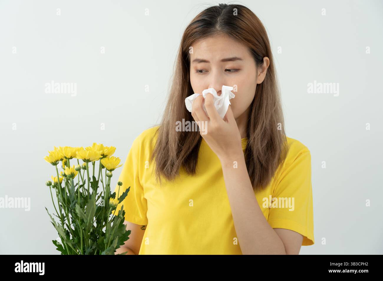 Allergie al polline, giovane donna asiatica starnuti in un fazzoletto o soffiare in una salvietta, allergica ai fiori primaverili selvatici o ai fiori in primavera. allerg Foto Stock