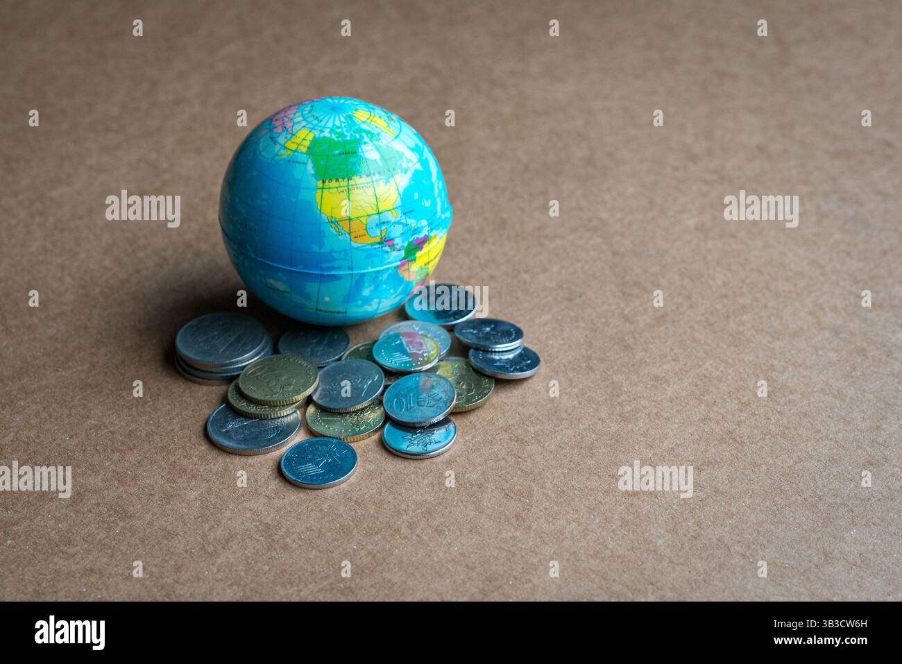 Globo con un mucchio di monete sulla superficie marrone. Copia spazio. Foto Stock