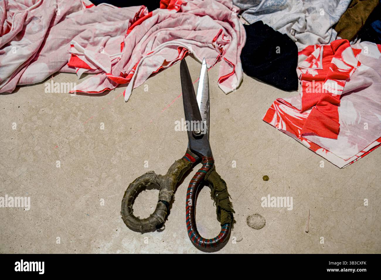 Forbici rustiche su un tavolo circondate da pezzi di tessuto colorati Foto Stock