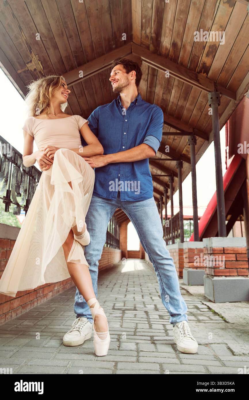 un partner innamorato circonda una ballerina che cammina attraverso la galleria in un giorno d'estate Foto Stock