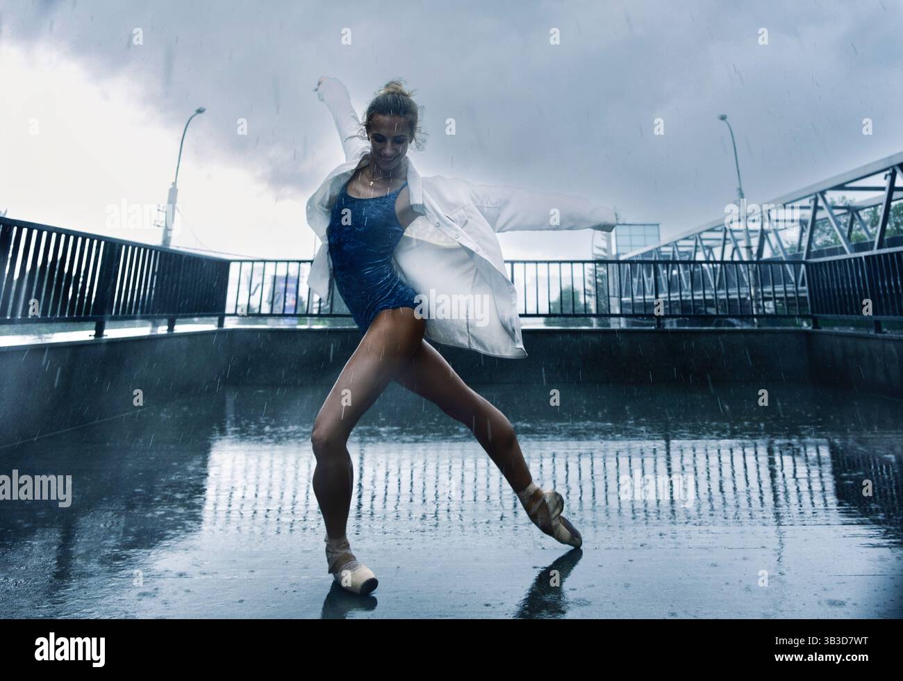 una ballerina balla sotto la pioggia per strada mentre cammina per la città in un giorno d'estate Foto Stock