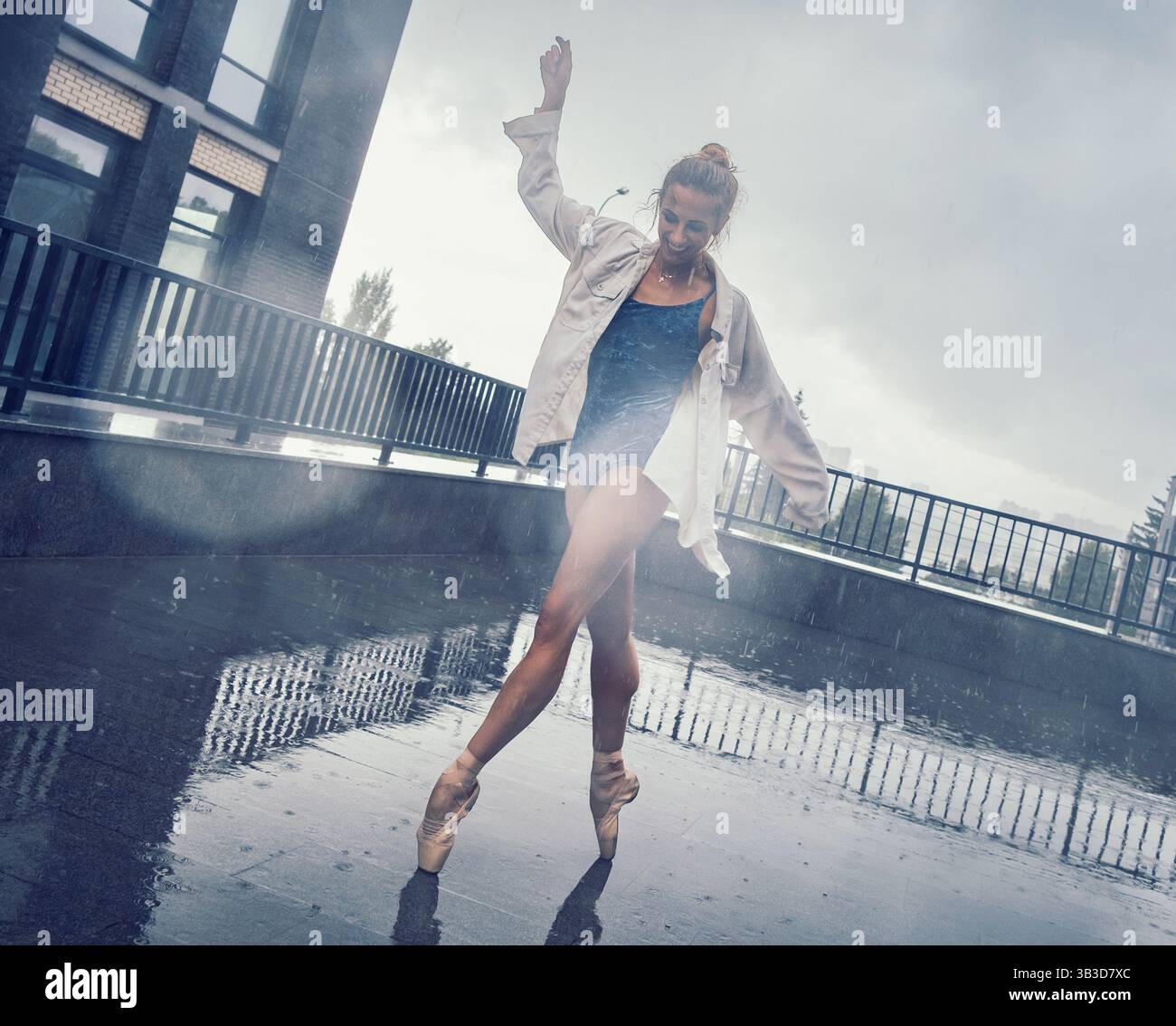una ballerina balla sotto la pioggia per strada mentre cammina per la città in un giorno d'estate Foto Stock