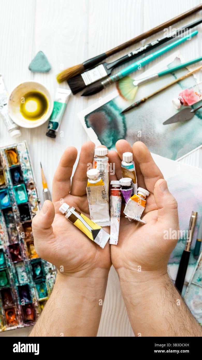 Artista con vista superiore pitture. Lezioni d'arte. Mani con vernici, pennelli, matite e altri strumenti per disegnare. Foto Stock