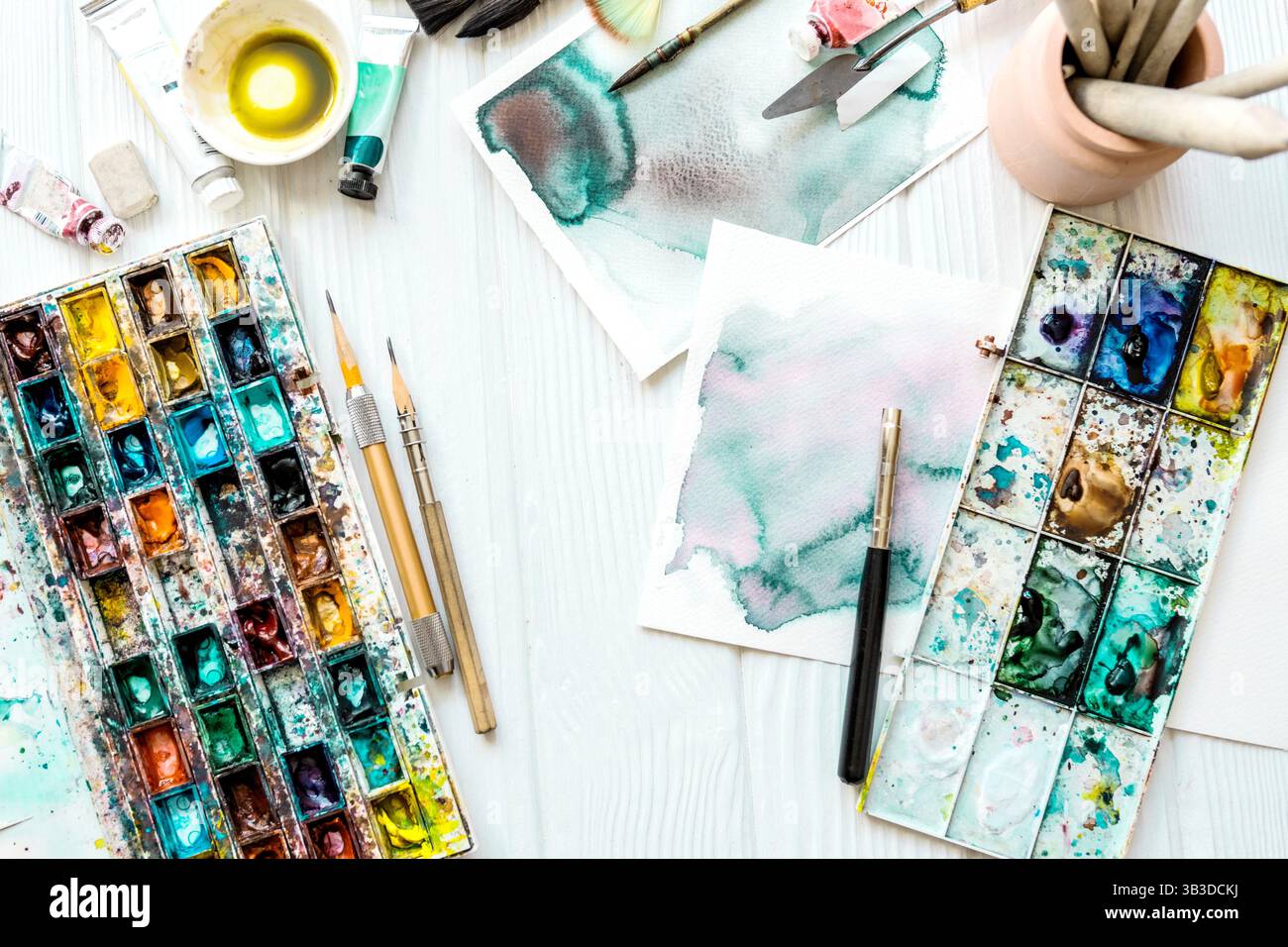 Artista con vista superiore pitture. Lezioni d'arte. Mani con vernici, pennelli, matite e altri strumenti per disegnare. Foto Stock