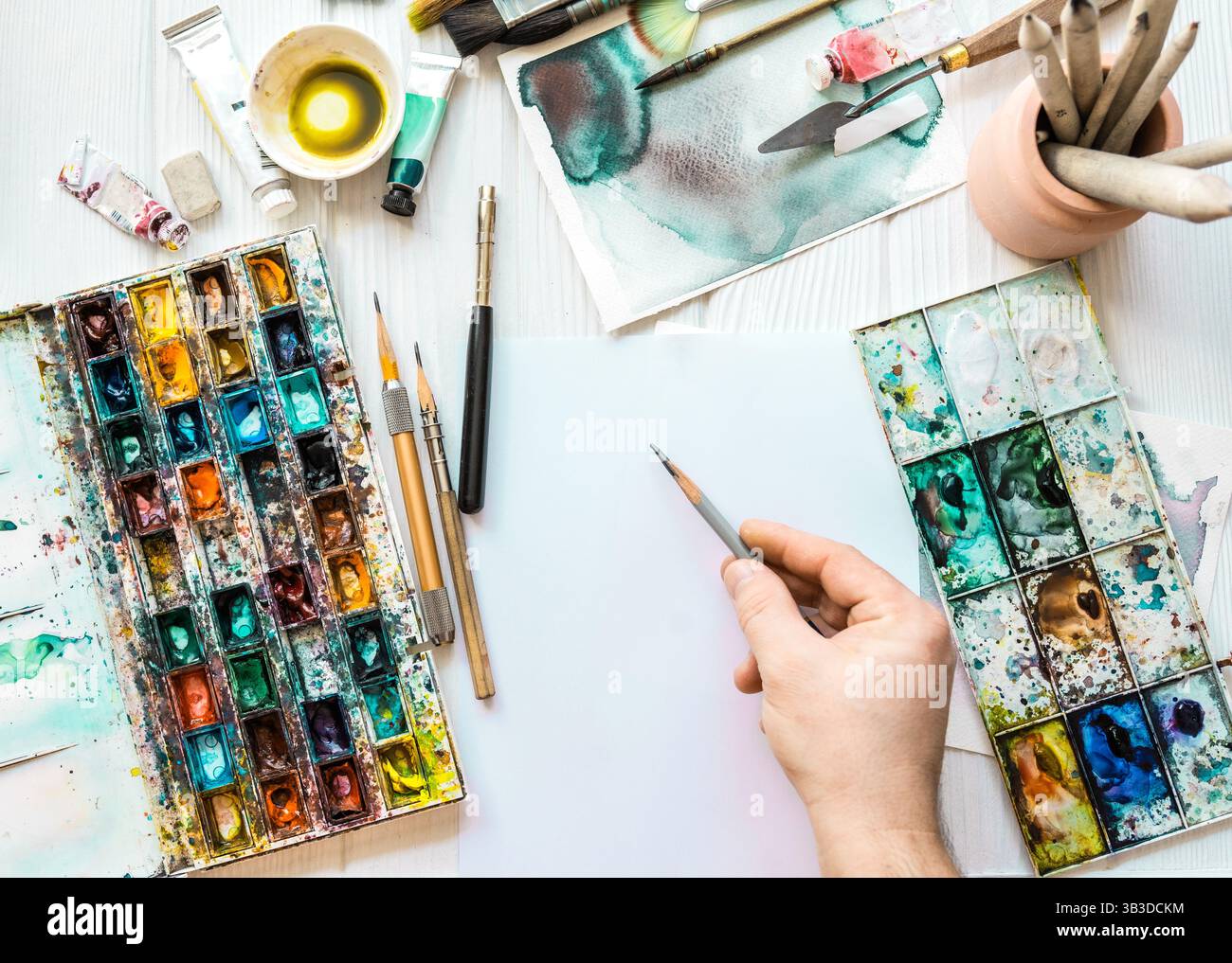 Artista con vista superiore pitture. Lezioni d'arte. Mani con vernici, pennelli, matite e altri strumenti per disegnare. Foto Stock