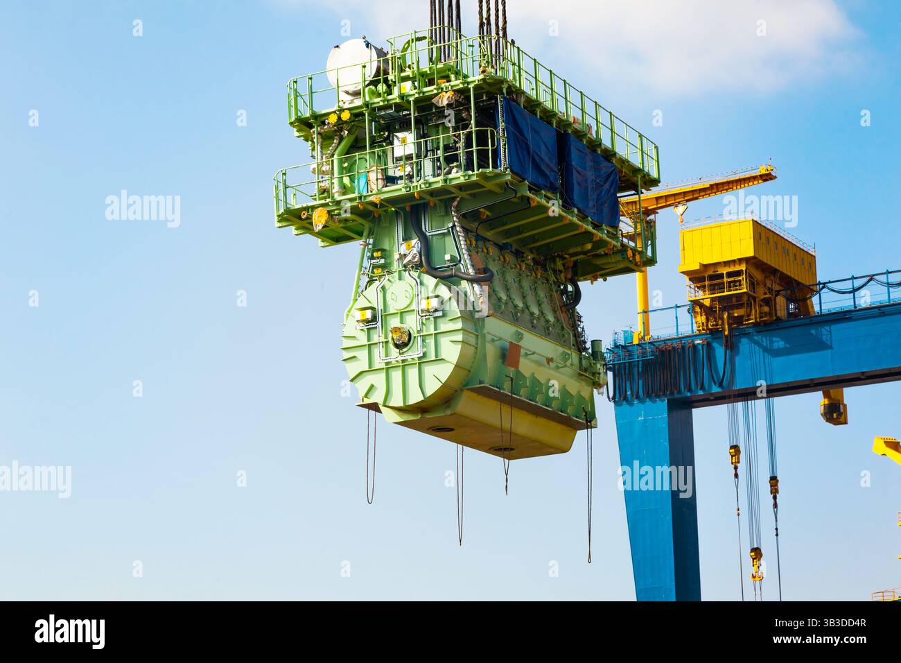 Trasporto di un grande motore marino tramite una gru portuale utilizzando cavi in acciaio. Foto Stock