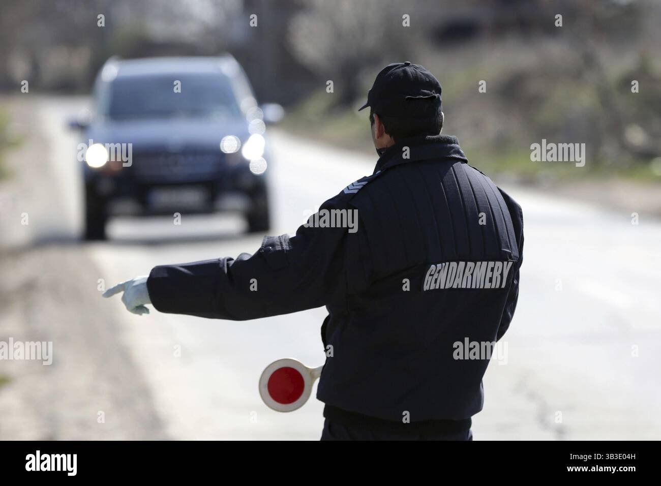 Un agente di polizia in uniforme da gendarmeria ferma un'auto per un controllo stradale Foto Stock
