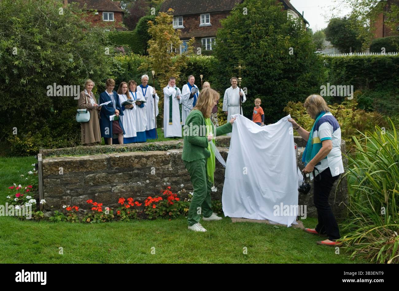 La placca di vestimento viene svelata da due membri del villaggio. Chiesa di Santa Maria pellegrinaggio di Kemsing a questo Santo pozzo. Il pozzo al centro del villaggio è dedicato a Sant'Editta di Wilton, figlia illegittima del re sassone Edgar I. la leggenda locale afferma che la sua Santa presenza ha dato proprietà curative dell'acqua. Pellegrinaggio annuale al pozzo a settembre. Kemsing, Kent, Inghilterra 13 settembre 2014. 2010 UK HOMER SYKES Foto Stock