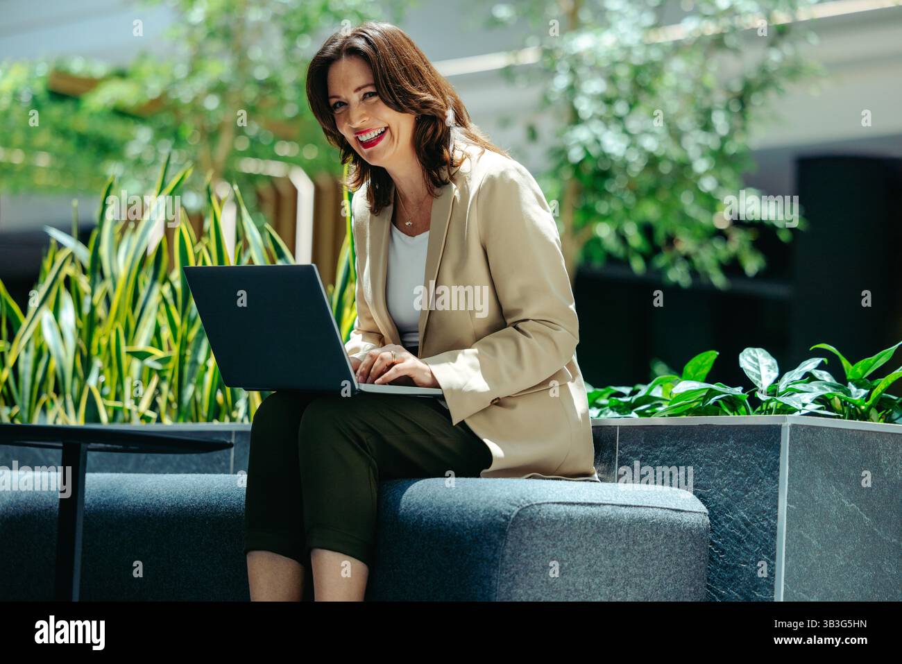 Un pianificatore finanziario lavora con fiducia su un notebook in un ufficio moderno con una vegetazione lussureggiante, trasudando professionalità, sostenibilità e cordialità. Foto Stock Un pianificatore finanziario lavora con fiducia su un notebook in un ufficio moderno con una vegetazione lussureggiante, trasudando professionalità, sostenibilità e cordialità. Foto Stock