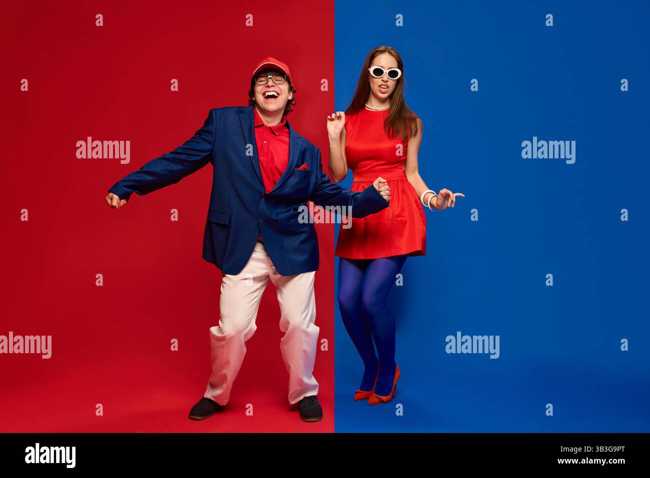 Coppia che balla giocosamente in un'audace configurazione rosso-blu Foto Stock