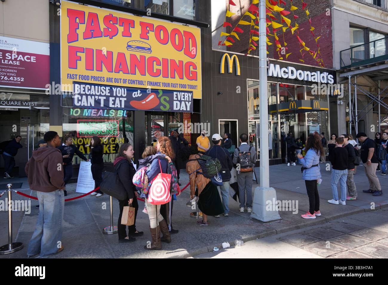 Gli amanti degli hamburger si esibiscono per ore fuori dal negozio ChiliÕs Grill & Bar ÒFast Food FinancingÓ a Union Square a New York giovedì 17 aprile 2025. L'attivazione del marchio è stata una promozione per il menu del ristorante chainÕs 3 for me, richiamando l'attenzione sul costo dei pasti di valore offerti in altre catene, tra cui il McDonaldÕs accanto. (© Richard B. Levine) Foto Stock