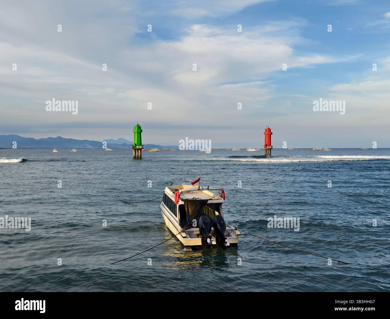 Sanur, Bali, Indonesia - 23 aprile 2025: Un motoscafo è ancorato tra due fari di navigazione, uno verde e uno rosso, galleggiante nel mare Foto Stock