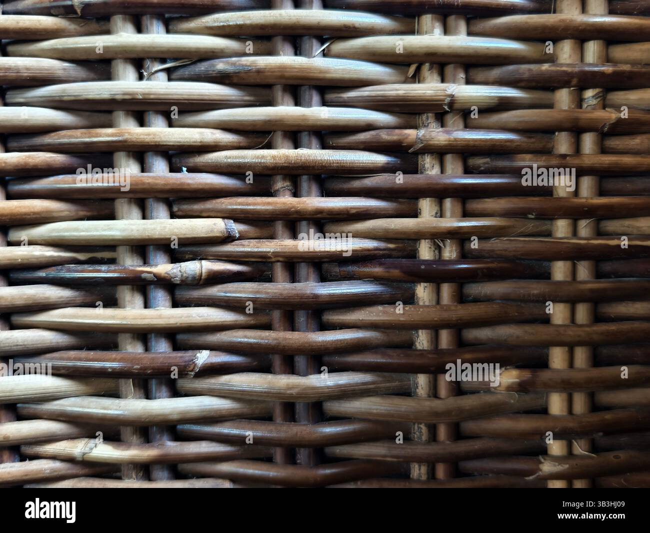 Vista ravvicinata di uno schema di ondulazione della superficie in rattan intrecciato, che mostra l'interlacciamento di materiali naturali Foto Stock