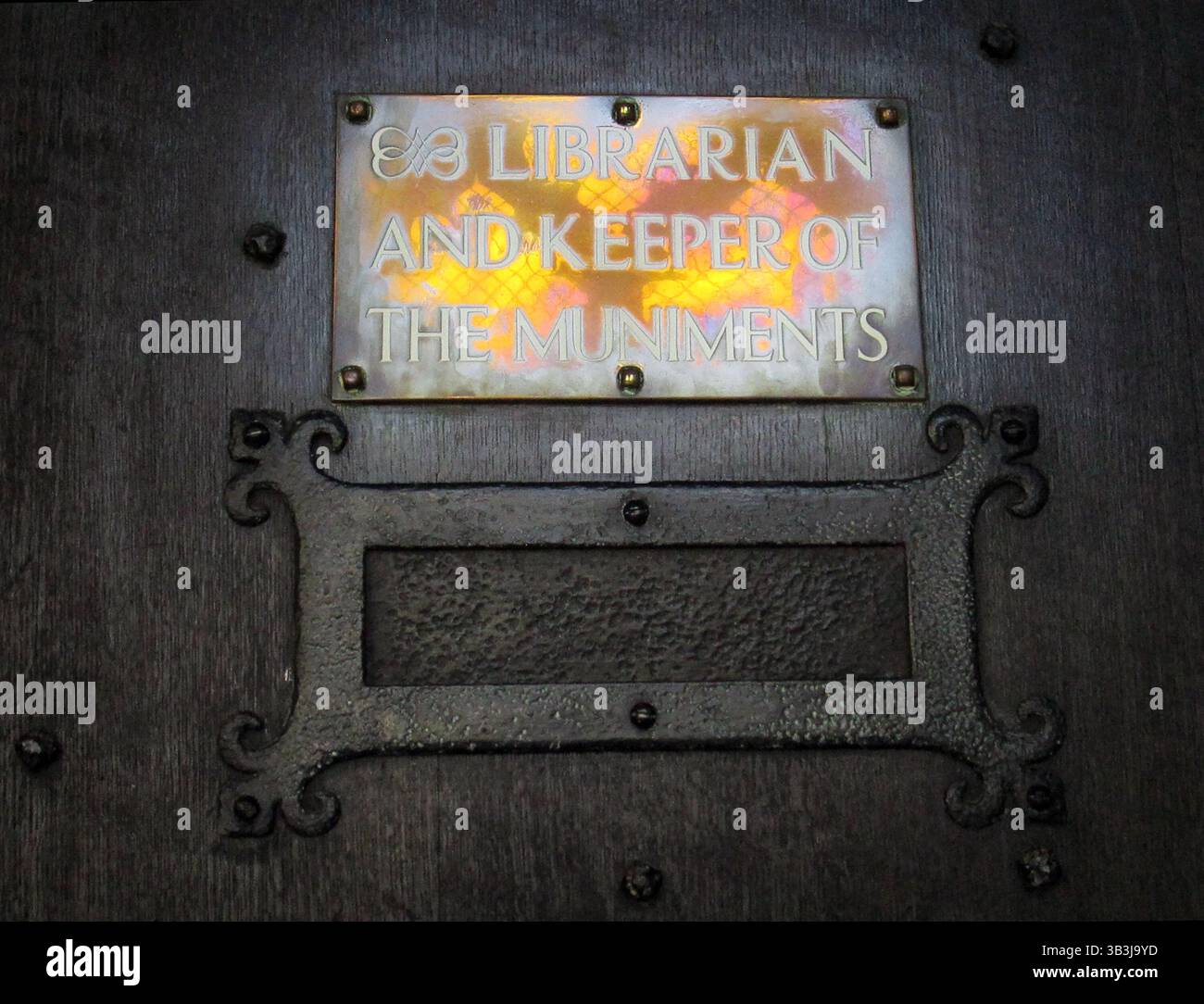 Placca in ottone Keeper of the Muniments, bibliotecaria dell'abbazia di Westminster, con luce riflessa dalle vetrate colorate Foto Stock