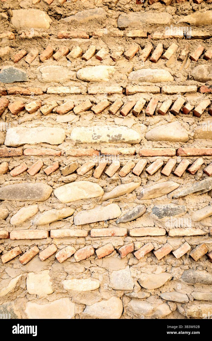 Primo piano di tradizionali pareti in pietra e mattoni georgiani con motivi diagonali in mattoni, che mostrano tecniche di muratura storiche Foto Stock