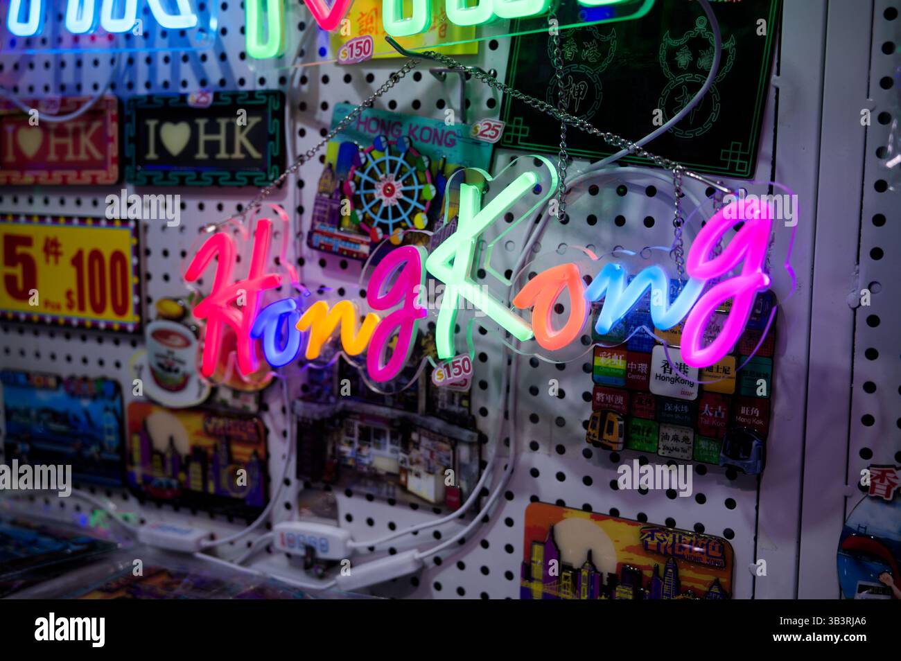 I vivaci cartelli al neon di "Hong Kong" si illuminano su una parete di souvenir in legno di pegboard Foto Stock