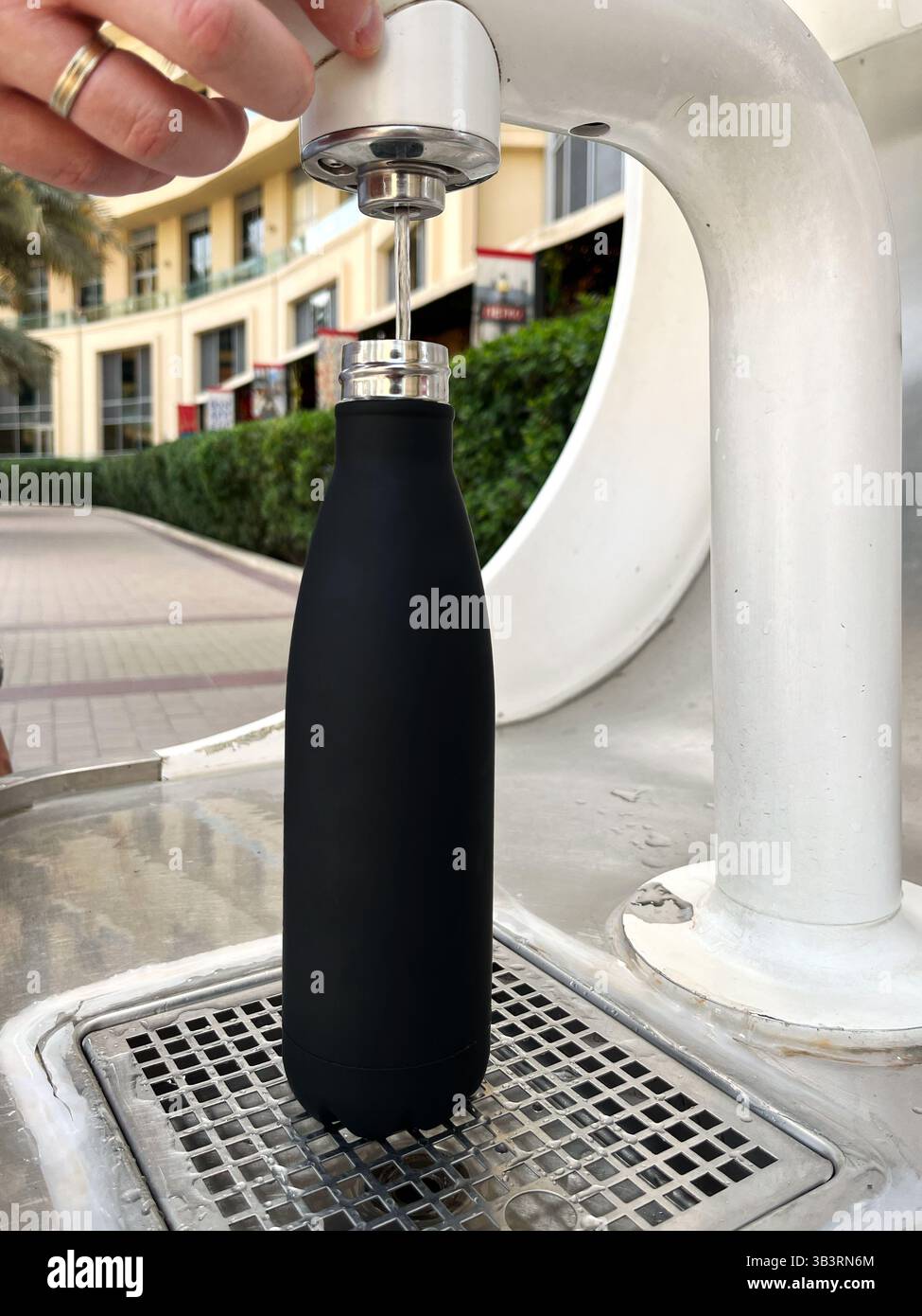 Riempimento della bottiglia d'acqua riutilizzabile presso la stazione dell'acqua pubblica all'aperto. Supporto per l'ecologia, sostenibile negli ambienti urbani Foto Stock