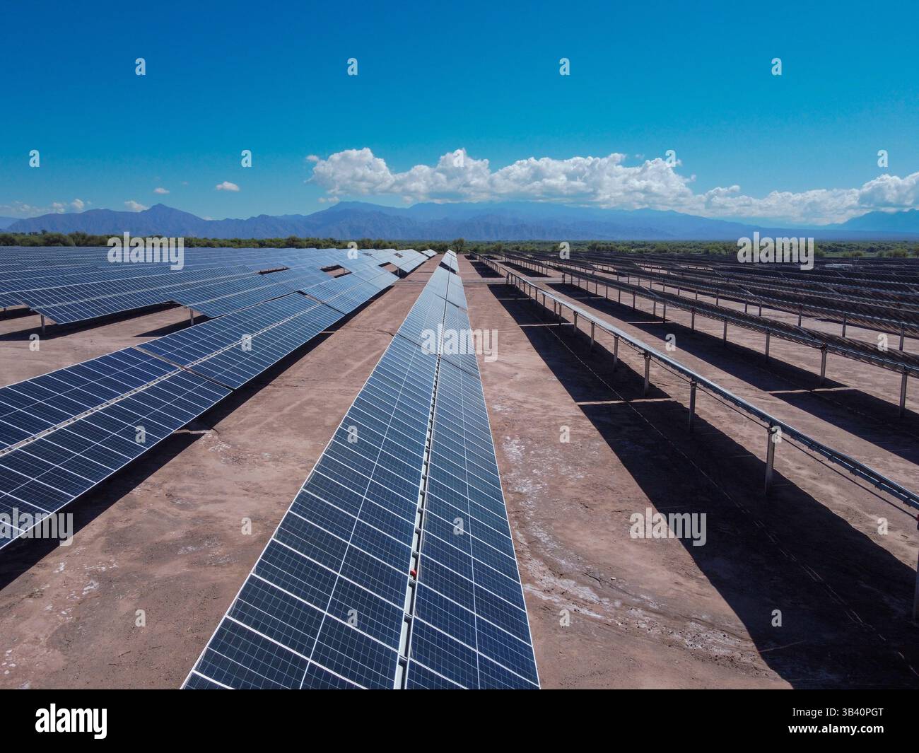 Sotto un cielo soleggiato che illumina i vasti campi di pannelli solari, sorge Tinogasta, con la maestosa presenza delle Ande in lontananza Foto Stock
