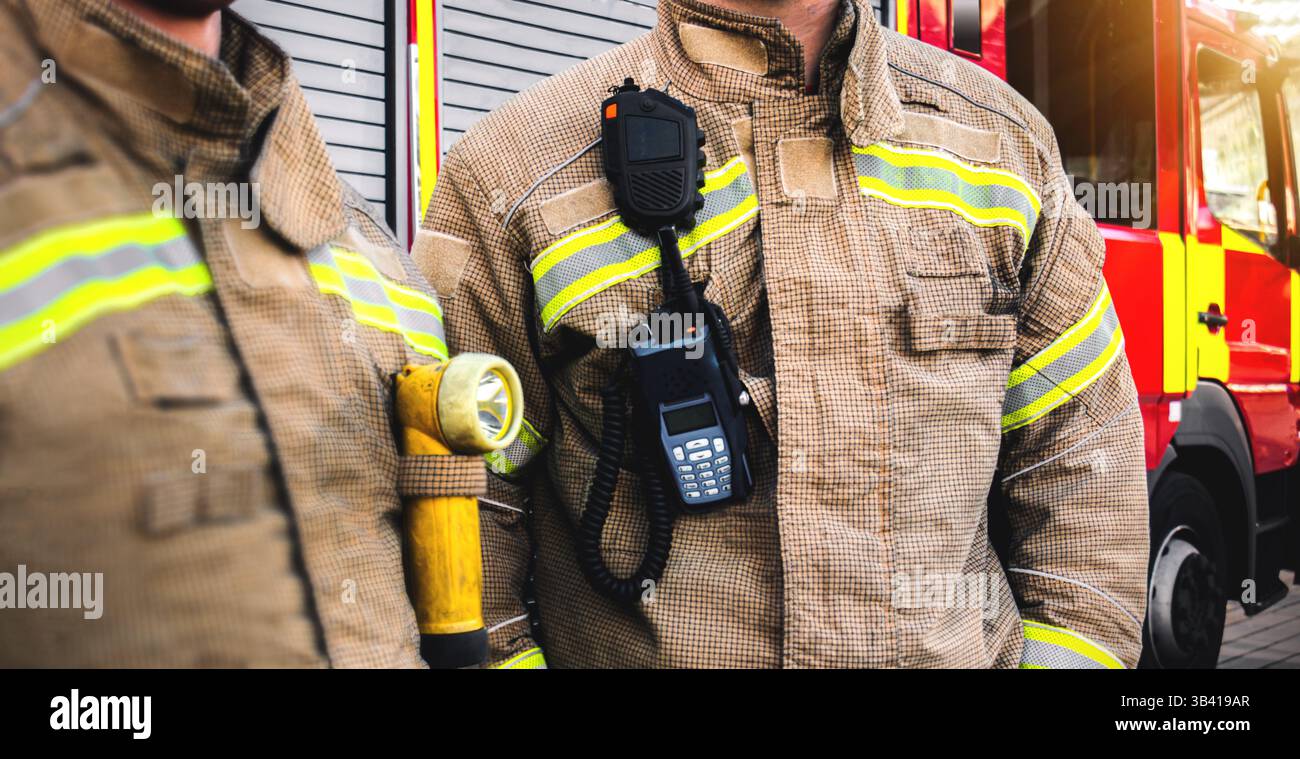 Squadra di vigili del fuoco - vigili del fuoco equipaggiati con servizi di emergenza di risposta uniforme dell'equipaggio antincendio e attrezzatura vicino al reparto motore antincendio rosso. autocarro. Foto Stock
