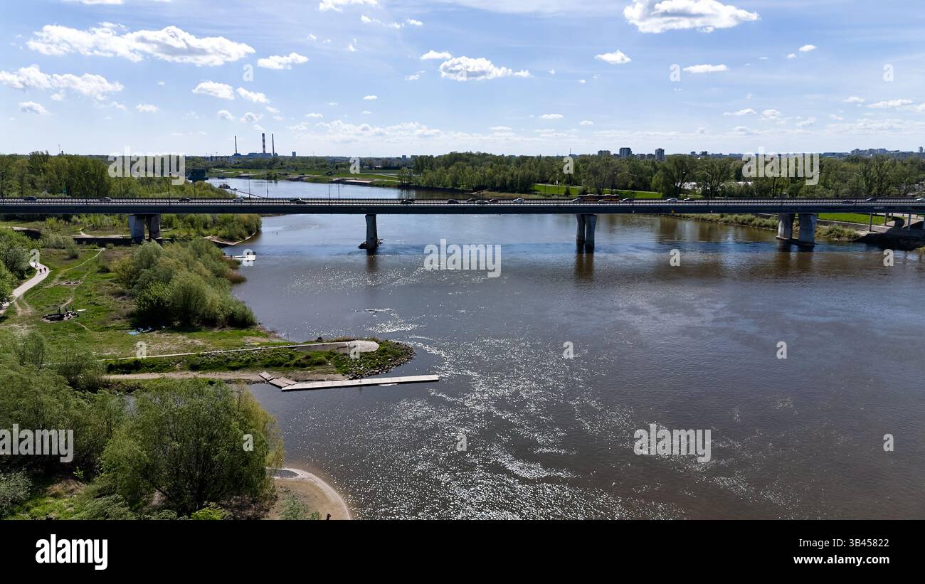 Il ponte attraversa un fiume con una città sullo sfondo. Il ponte è una grande struttura che collega due lati del fiume. Varsavia 20.04.2025 Polonia Foto Stock