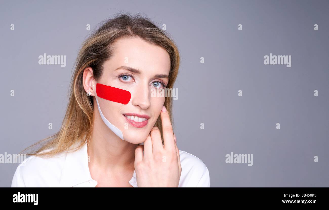Una bella donna con nastri sul viso dimostra una procedura cosmetica per sollevare e stringere la pelle senza intervento chirurgico. Foto Stock