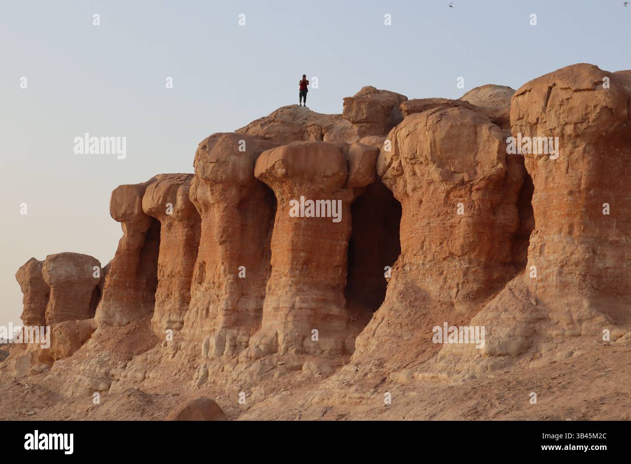 Un uomo in cima ai pilastri occidentali del monte al Qarah è oscurato dalle formazioni rocciose. Hofuf, al-Ahsa, Regno dell'Arabia Saudita. Foto di Tuvyan Savuy Foto Stock