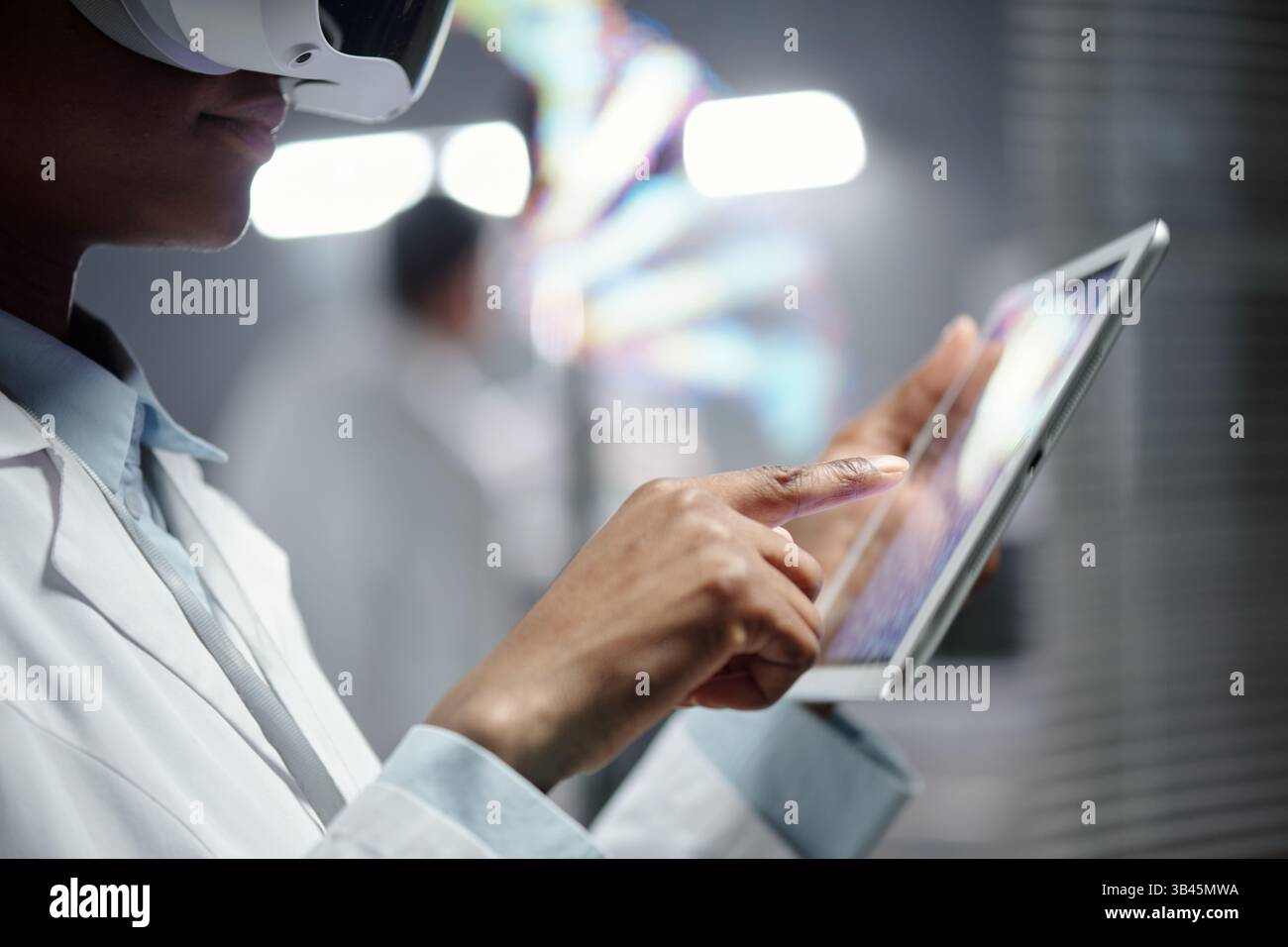Professionisti in laboratorio che utilizzano cuffie per realtà virtuale e tablet per ricerche e analisi avanzate. Applicazioni tecnologiche innovative che migliorano lo studio scientifico Foto Stock