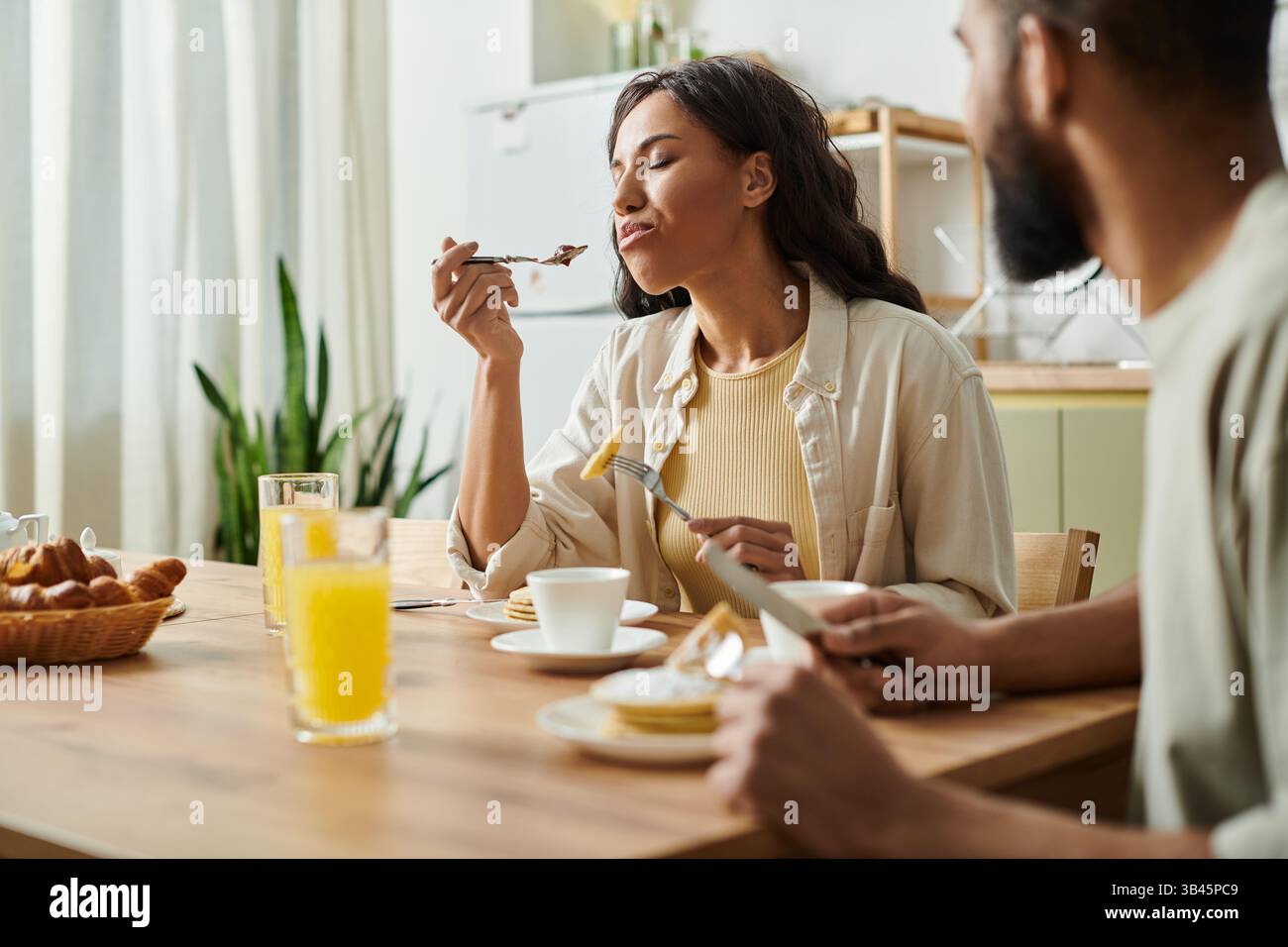 Una coppia amorevole si gode un delizioso pasto insieme nella loro accogliente casa, assaporando ogni momento. Foto Stock