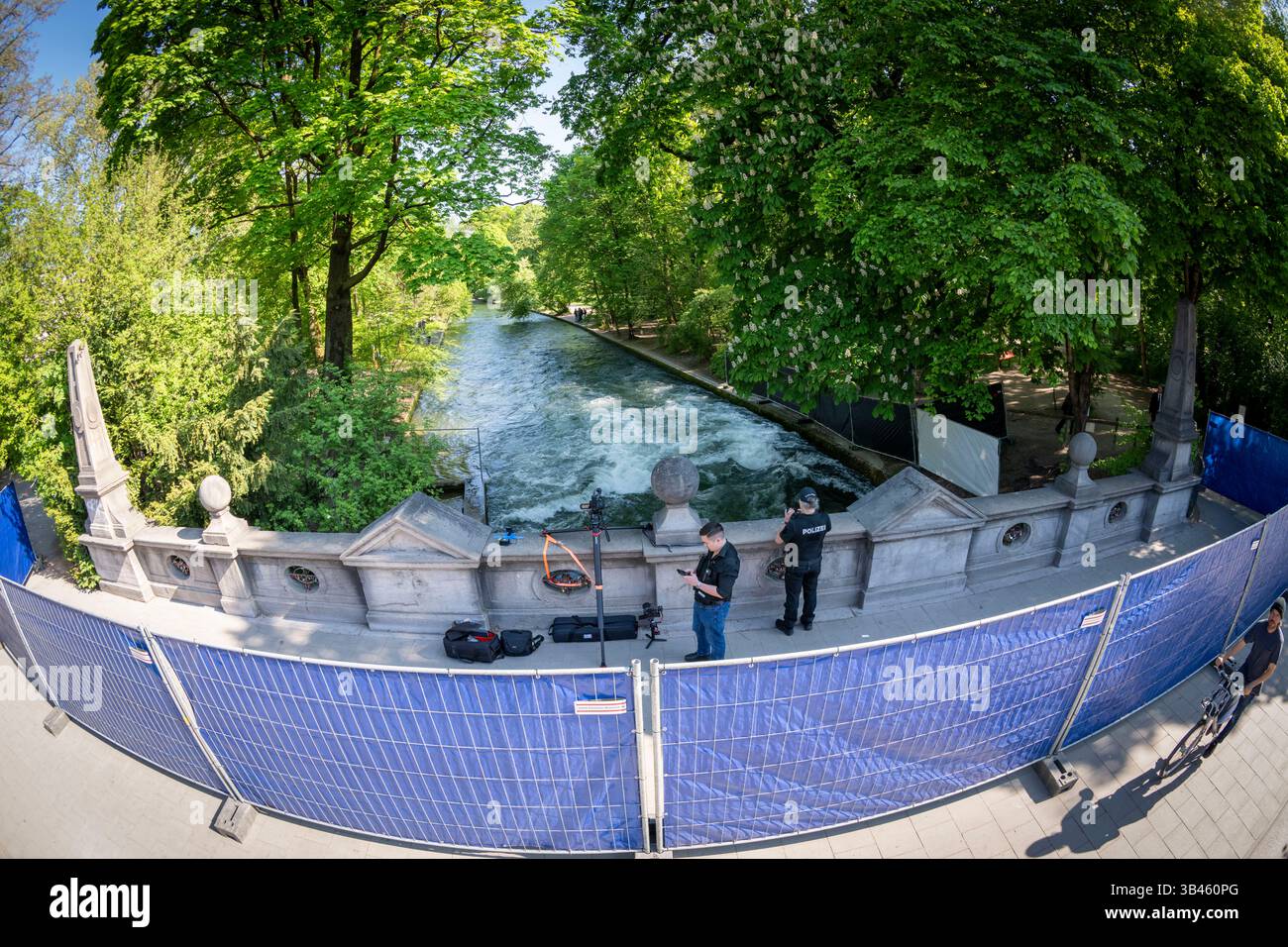 Monaco, Germania. 30 aprile 2025. Le barriere con teloni blu contro gli occhi indiscreti si trovano su un ponte che conduce sopra l'Eisbach. Un surfista caduto sull'onda di Eisbach sotto nel giardino inglese è morto in ospedale la scorsa settimana. Ora la polizia sta abbassando l'acqua per indagare sulla possibile causa. Crediti: Peter Kneffel/dpa/Alamy Live News Foto Stock