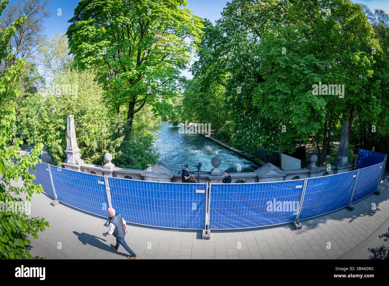Monaco, Germania. 30 aprile 2025. Le barriere con teloni blu contro gli occhi indiscreti si trovano su un ponte che conduce sopra l'Eisbach. Un surfista caduto sull'onda di Eisbach sotto nel giardino inglese è morto in ospedale la scorsa settimana. Ora la polizia sta abbassando l'acqua per indagare sulla possibile causa. Crediti: Peter Kneffel/dpa/Alamy Live News Foto Stock