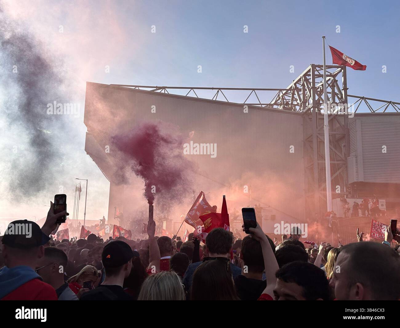 I tifosi festeggiano la vittoria della Premier League nelle strade fuori Anfield con bandiere e razzi rossi, 27 aprile 2025. - Immagine stock catturata con smartphone