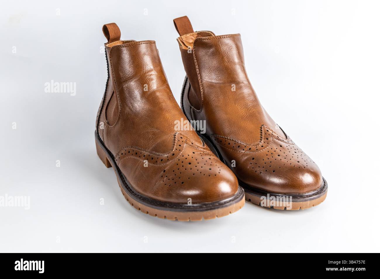 Primo piano di stivali Chelsea in pelle marrone con design a punta alata in brogue e suola robusta. Foto Stock