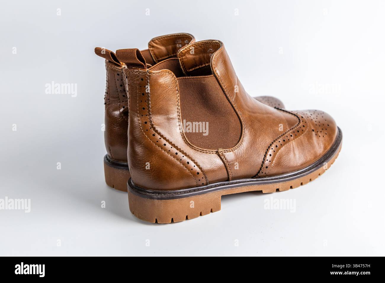 Eleganti stivali Chelsea marroni con motivo brogue traforato e design slip-on. Foto Stock
