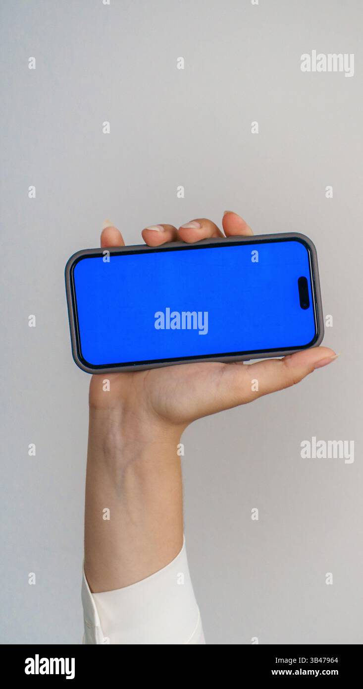 modello con schermata blu vuota del telefono cellulare. mani di adolescente che tiene in mano messaggi di testo usando il cellulare.sfondo spazio vuoto per la pubblicità. contatto con i lavoratori Foto Stock