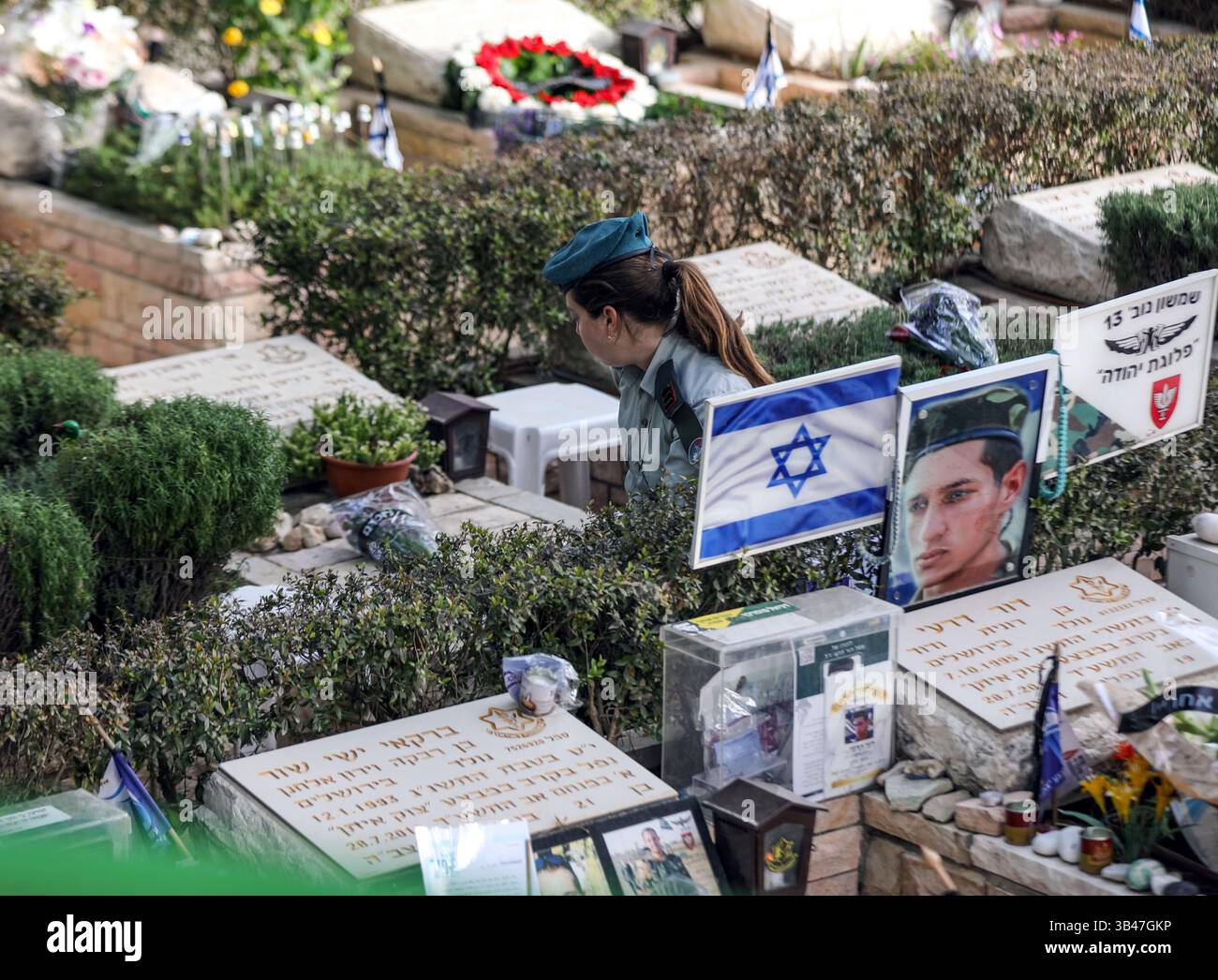 Gerusalemme, Israele. 30 aprile 2025. Israele sta commemorando il Memorial Day per i soldati caduti nelle cerimonie nei cimiteri militari. Una donna ufficiale dell'IDF seduta accanto a una tomba, circondata da molte altre tombe credito: Yoram Biberman/Alamy Live News. Foto Stock