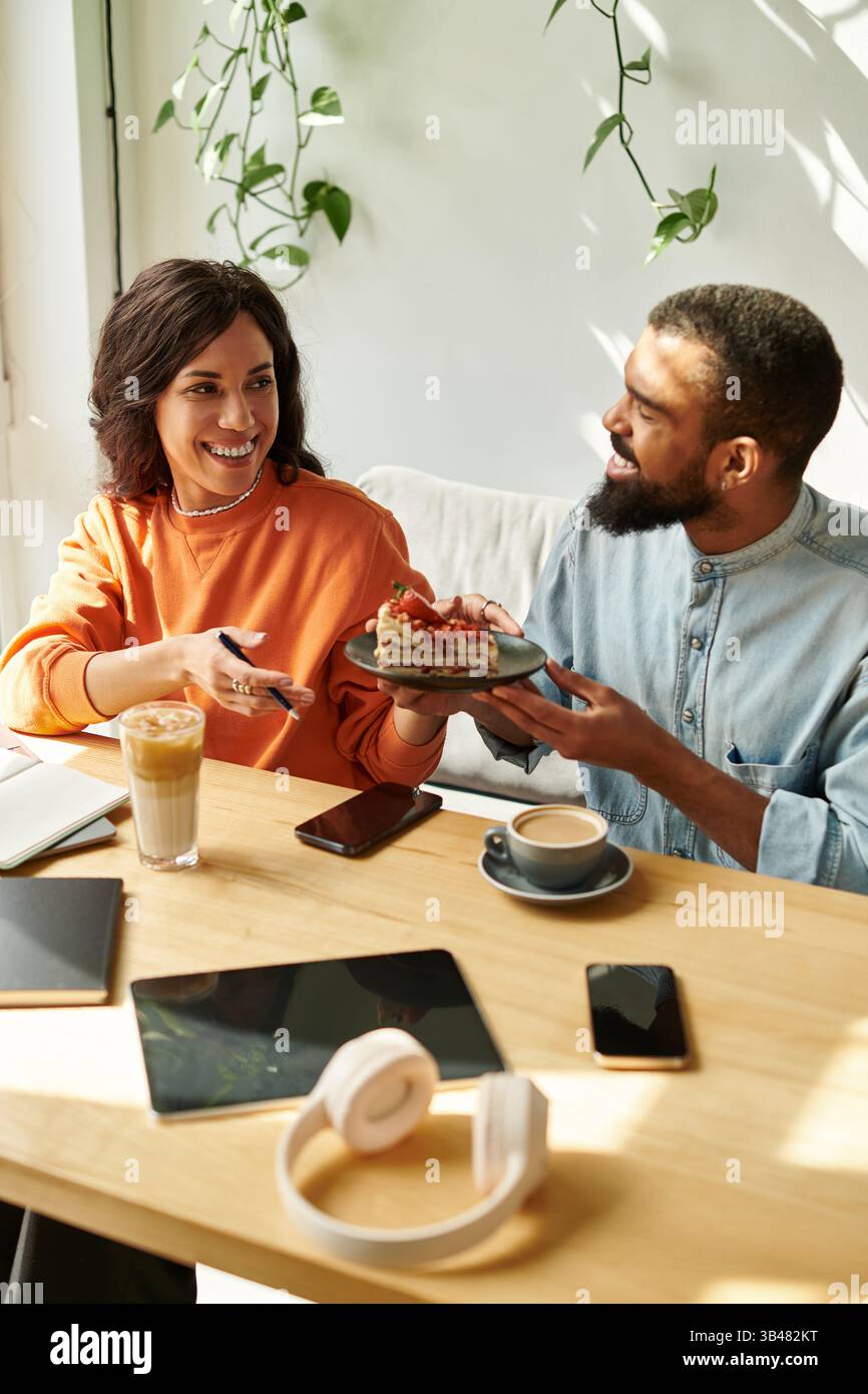 Una coppia afroamericana lavora insieme su progetti freelance mentre si gode una gustosa sorpresa. Foto Stock