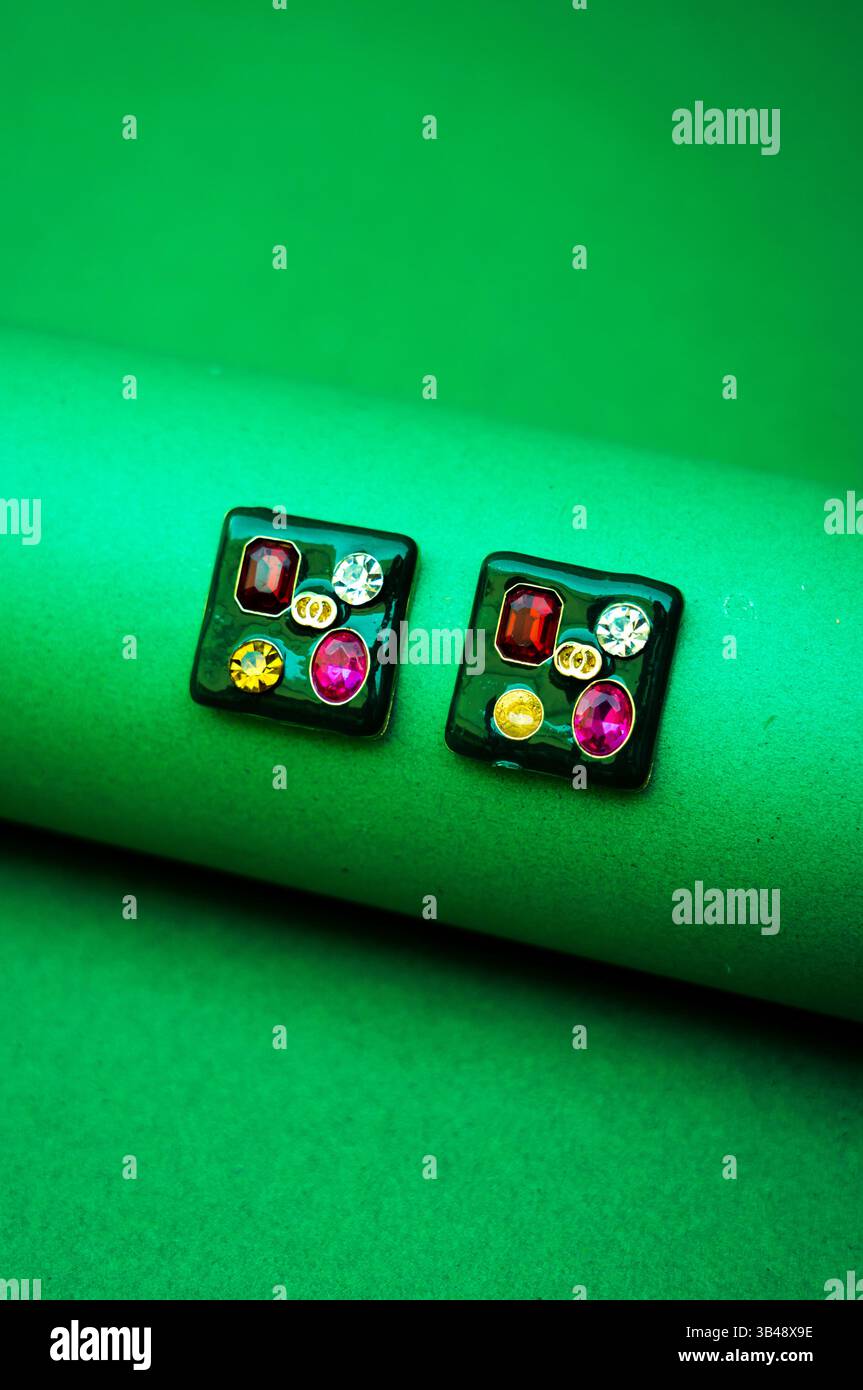 Jewelry Aesthetic: Orecchini su sfondo verde, orecchini stilizzati con un tema incentrato sulla natura, catturati su uno sfondo eco-verde. Foto Stock