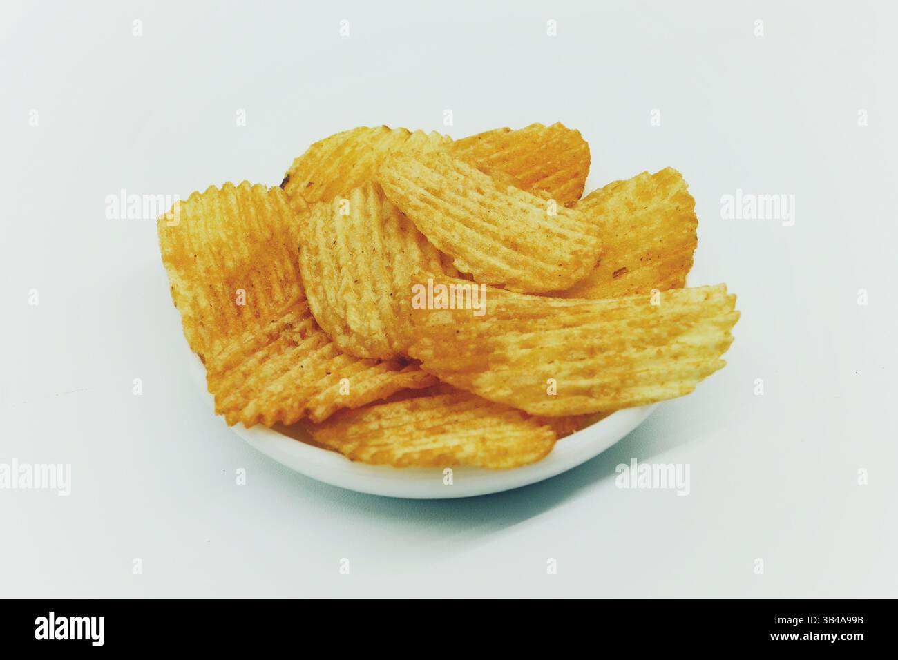 Spuntino con patatine a fette sottili e ruvide con spruzzi di condimento isolati su bianco. Foto Stock