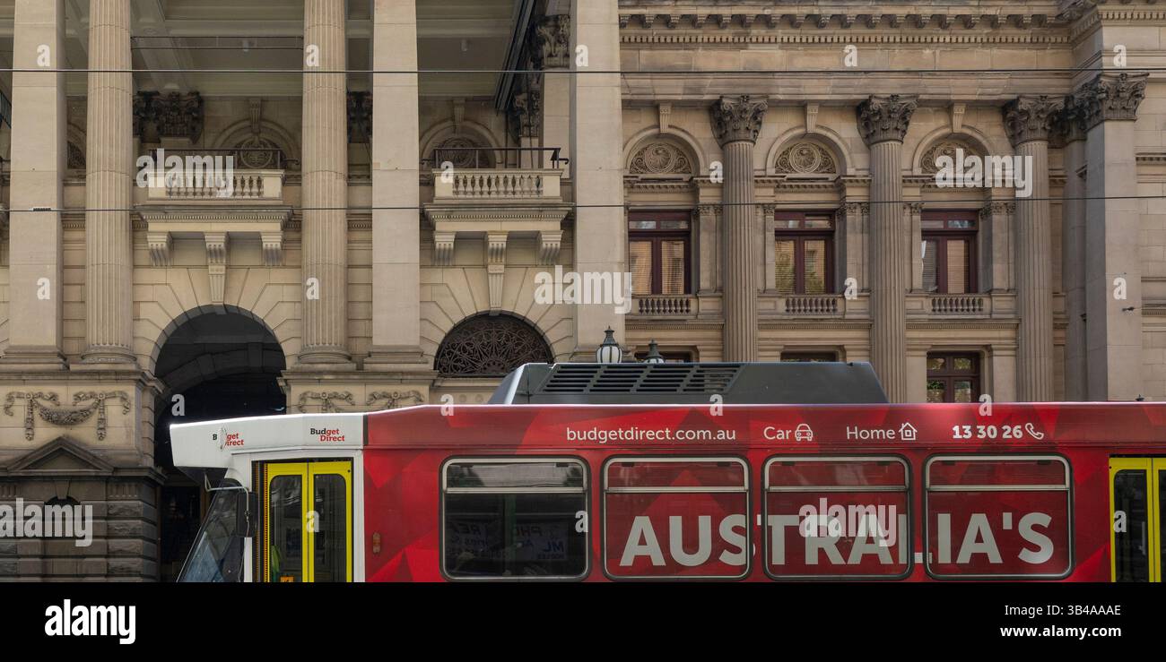 Vista laterale di un tram cittadino di trasporto pubblico di fronte a un edificio nel quartiere centrale degli affari di Melbourne, Victoria, Australia Foto Stock