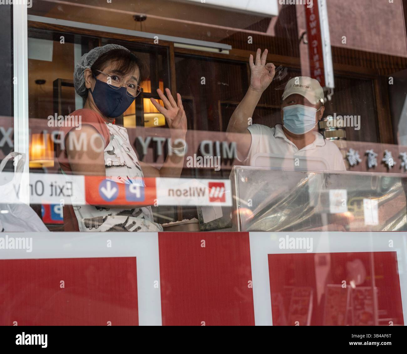 Vista dei lavoratori del ristorante che sorridono e sventolano attraverso una finestra di un ristorante di cucina cinese a China Town, Melbourne City, Victoria, Australia Foto Stock