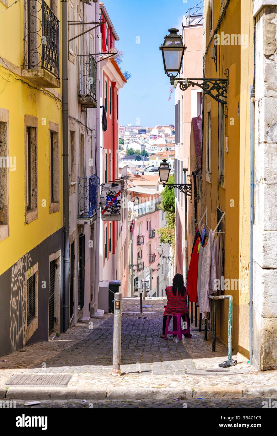 Stretta strada acciottolata con tradizionali edifici colorati e storici lampioni nella città vecchia di Lisbona, Portogallo. Foto Stock